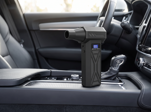 Handheld blower resting on a car's centre console next to the gear selector